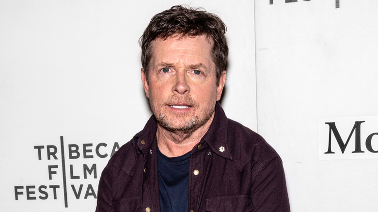 Michael J. Fox posing for photos in a brown jacket at the Tribeca Film Festival
