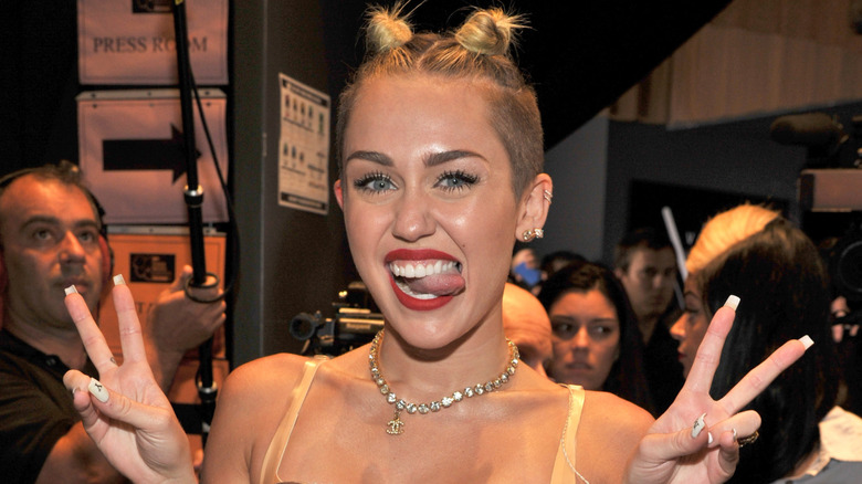 Miley Cyrus posing with peace signs and tongue out