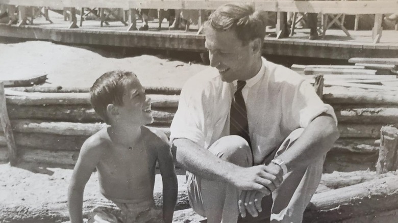 A young Chevy Chase sitting at the beach with his father