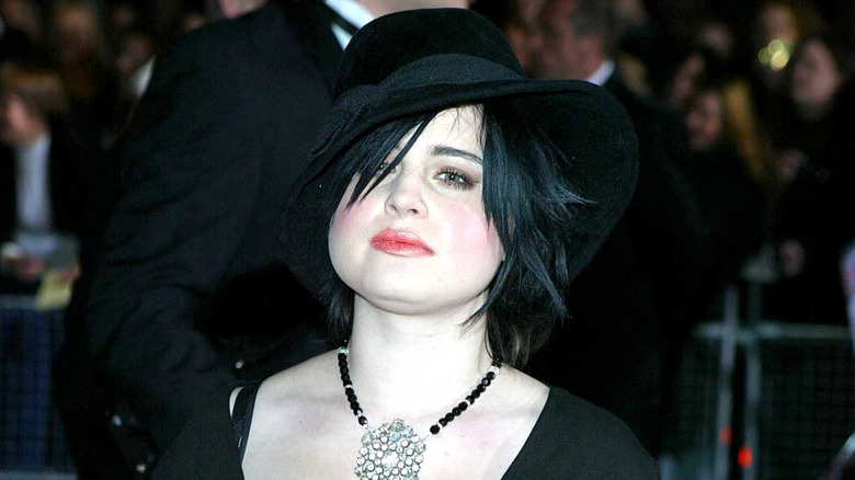 Kelly Osbourne in black hat with black hair and large necklace