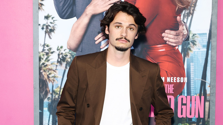 Dylan Jagger Lee posing at the premiere of The Naked Gun in a brown jacket and white shirt