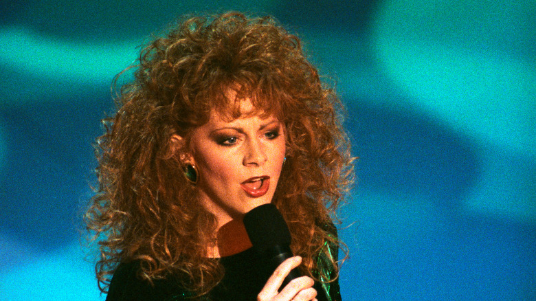 Reba McEntire talking into a microphone onstage