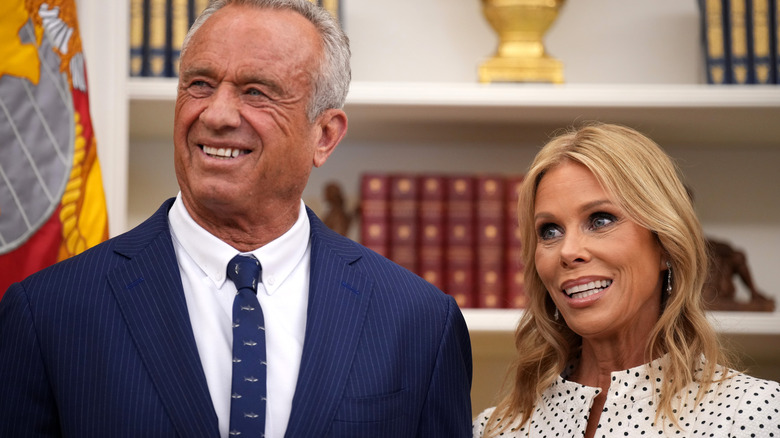 Cheryl Hines seemingly forcing a smile next to RFK Jr. in the Oval Office