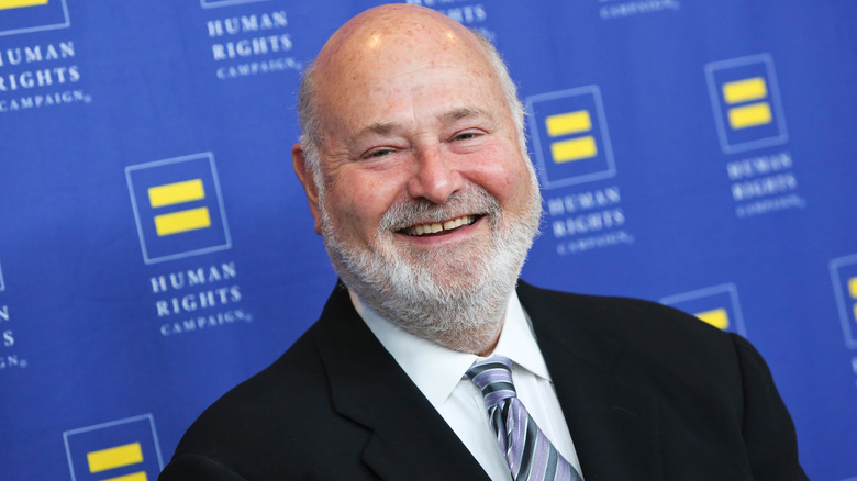 Rob Reiner smiling while posing at an event in a black suit