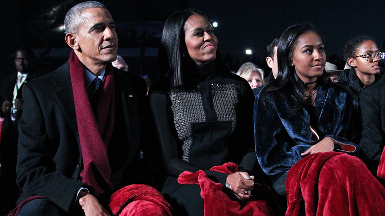 Sasha Obama seated next to Michelle and Barack Obama