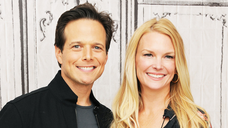 Scott Wolf wearing black and Kelley Wolf wearing a black floral dress