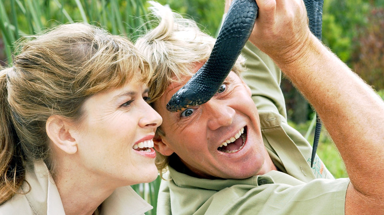 Steve Irwin holding up a snake next to Terri Irwin