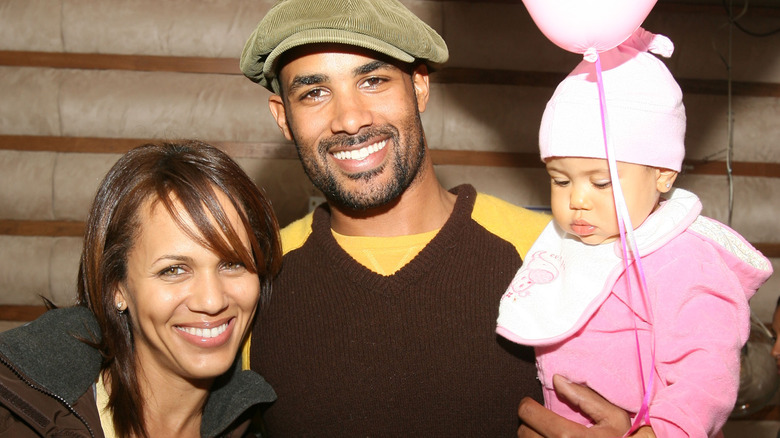 Nicole Ari Parker smiling with her husband and daughter 