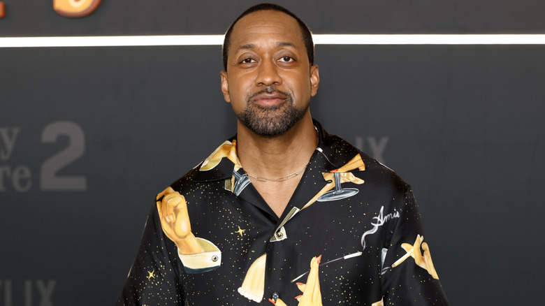 Jaleel White posing on the red carpet in a black shirt with gold detailing