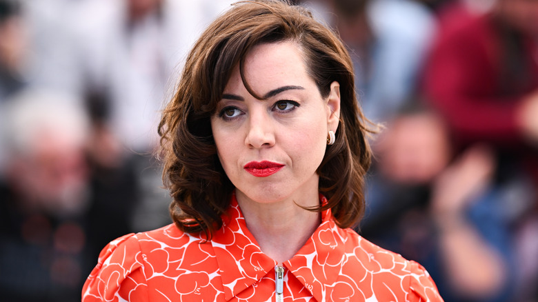 Aubrey Plaza attending a Megalopolis photo-call wearing an orange dress