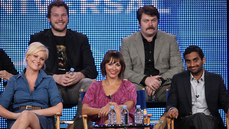 Amy Poehler, Chris Pratt, Rashida Jones, Nick Offerman, and Aziz Ansari smiling onstage during Parks and Recreation event