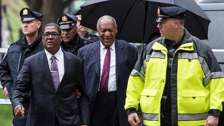 Bill Cosby being led by police in the rain