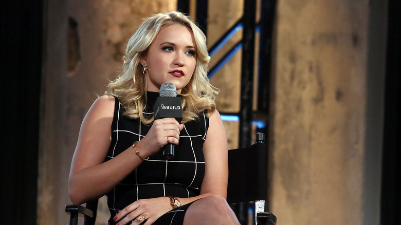 Emily Osment on the mic in a black checked dress