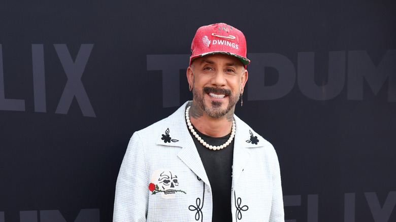 AJ McLean in a white jacket and red cap