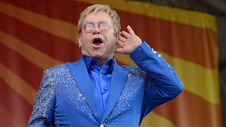 Elton John puts his hand to his ear onstage