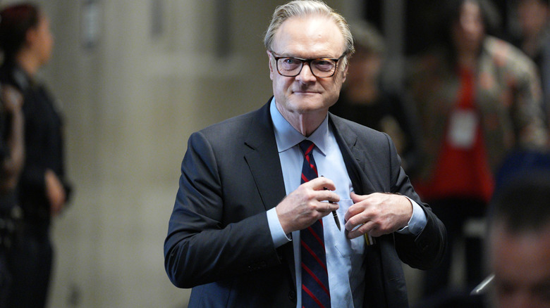 Lawrence O'Donnell smiling as he walks among a crowd