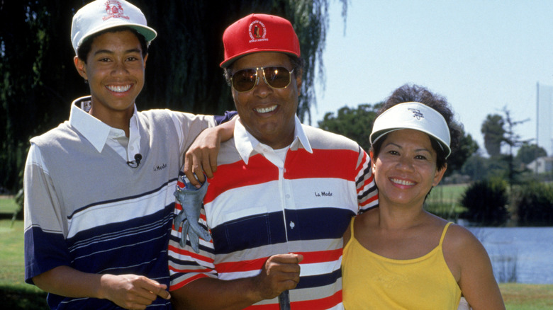 Tiger Woods posing with his parents in 1990