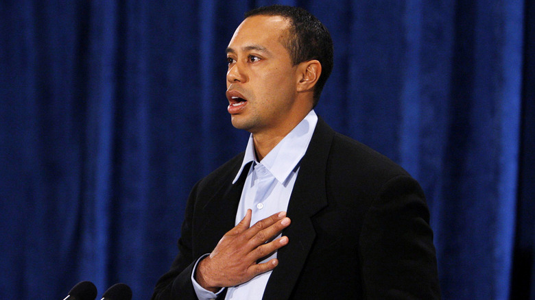 Tiger Woods making a public statement in front of blue curtains