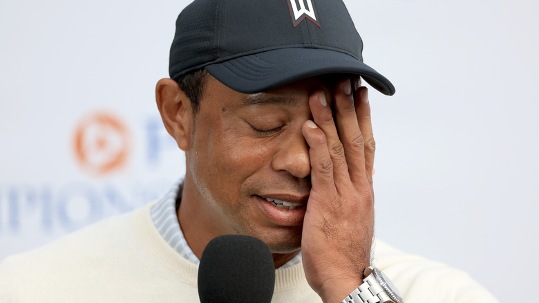 Tiger Woods covering face while speaking with the press