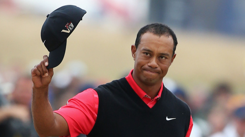 Tiger Woods waving with his hat in 2013