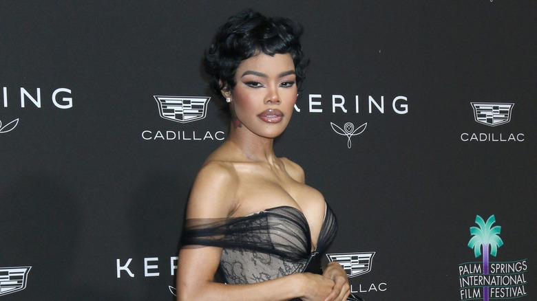Teyana Taylor posing at an event with a revealing black dress
