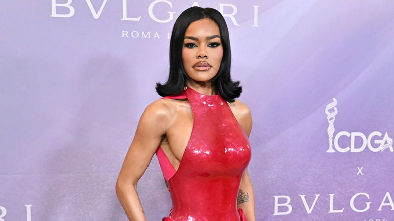 Teyana Taylor posing at an event with a shiny red outfit