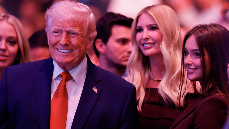 A smiling Ivanka Trump standing behind Donald Trump