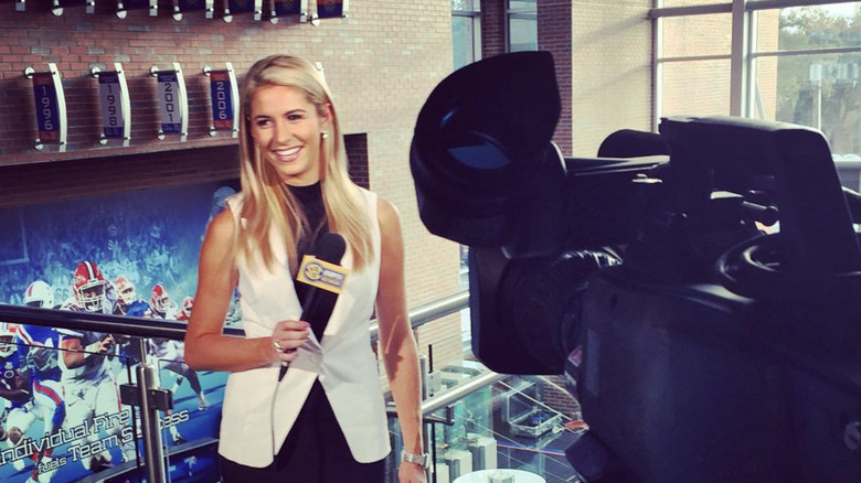 Laura Rutledge smiling on set in front of studio camera and holding mic