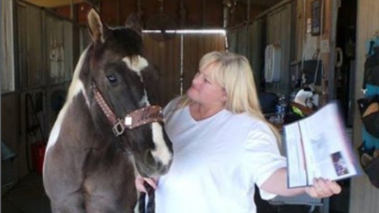 Debbie Rowe smiling at a horse while holding a piece of paper 2013