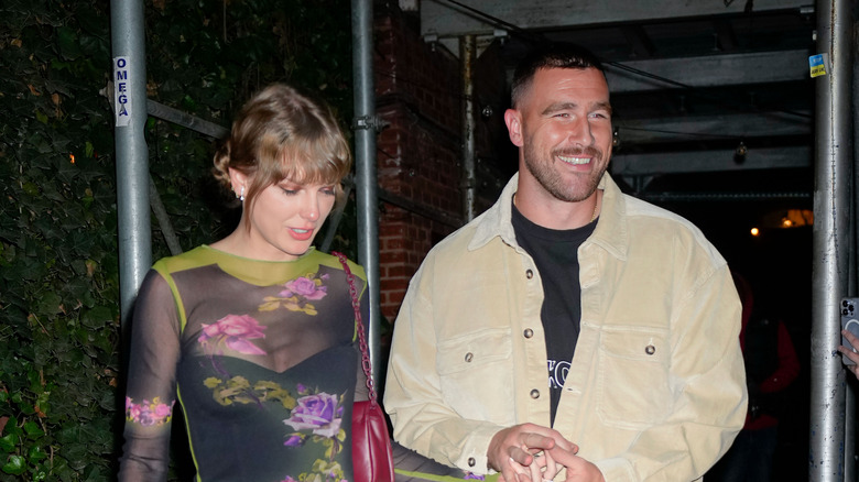 Travis Kelce and Taylor Swift walking out of a restaurant