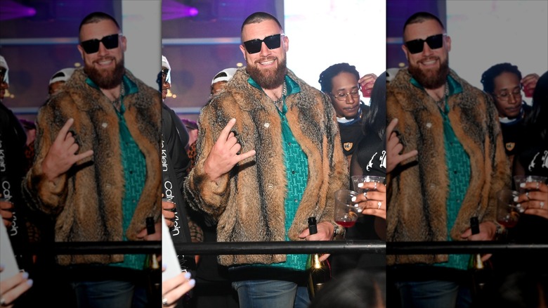 Travis Kelce poses in a fur coat and large sunglasses.