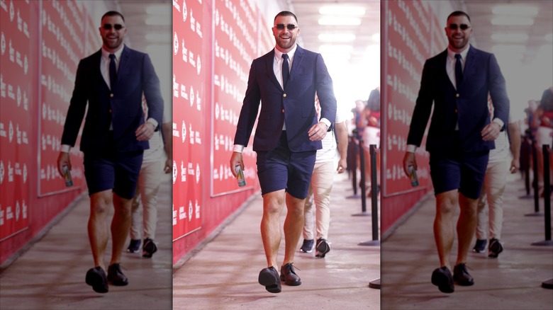 Travis Kelce strolling down the tunnel in a suit with shorts.