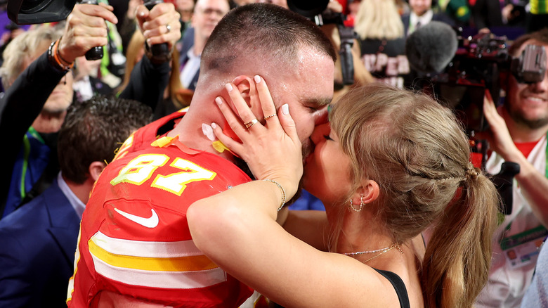 Travis Kelce and Taylor Swift kissing on the field after the Super Bowl