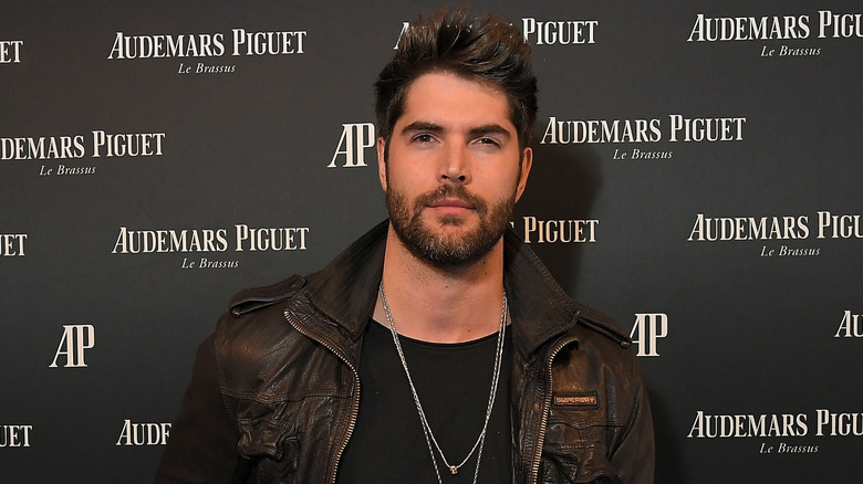 Nick Bateman in a black shirt and brown leather jacket