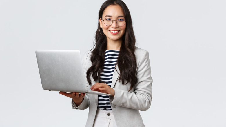 Woman in work attire carrying a laptop