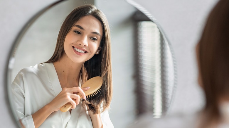 Woman brushes her hair in mirror