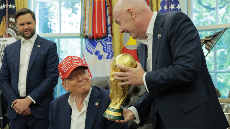 FIFA president Gianni Infantino showing the World Cup trophy to Donald Trump as JD Vance watches