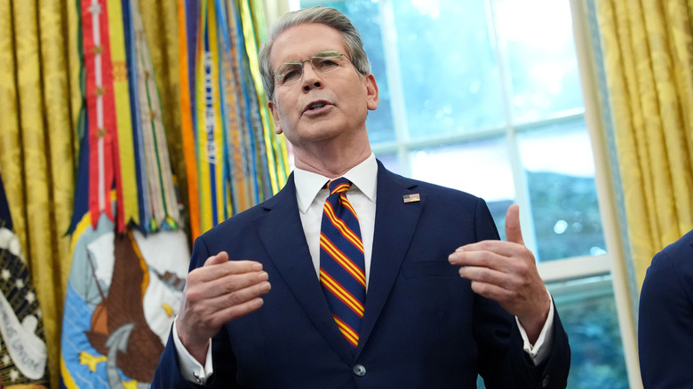 Scott Bessent speaking while raising his hands in the Oval Office