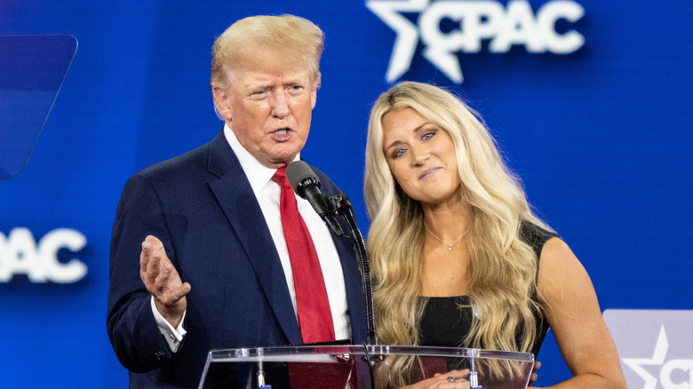 Donald Trump speaking at CPAC 2022 with Riley Gaines standing next to him.