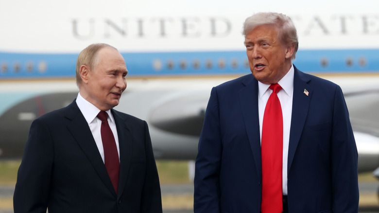 Donald Trump and Vladimir Putin speaking and smiling in suits in front of Air Force One