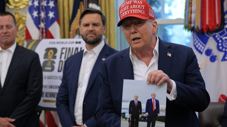Donald Trump proudly holding up a photo of himself and Vladimir Putin.