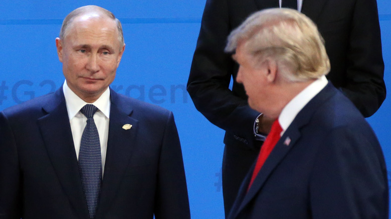 Vladimir Putin and Donald Trump looking at each other while wearing suits