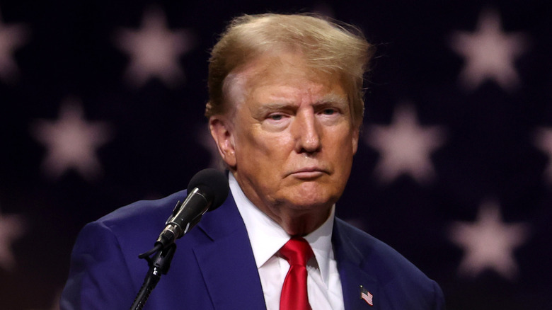 Donald Trump looking melancholy at the microphone