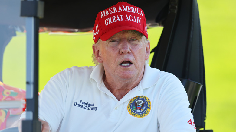 Donald Trump in golf cart red MAGA cap
