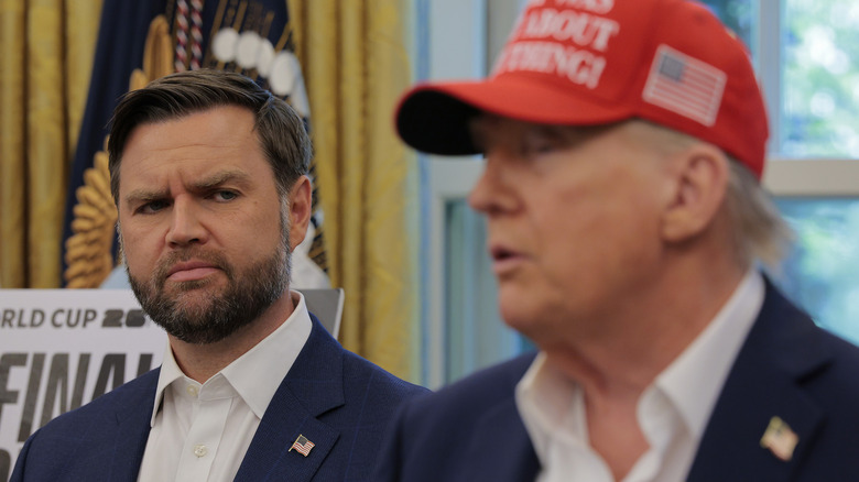 JD Vance giving Donald Trump side-eye while both wear navy suits with American flag pins