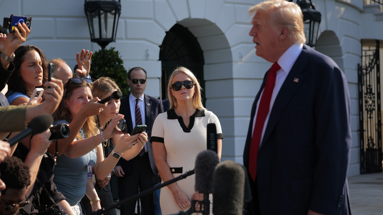 Karoline Leavitt looking at Donald Trump as he speaks to journalists