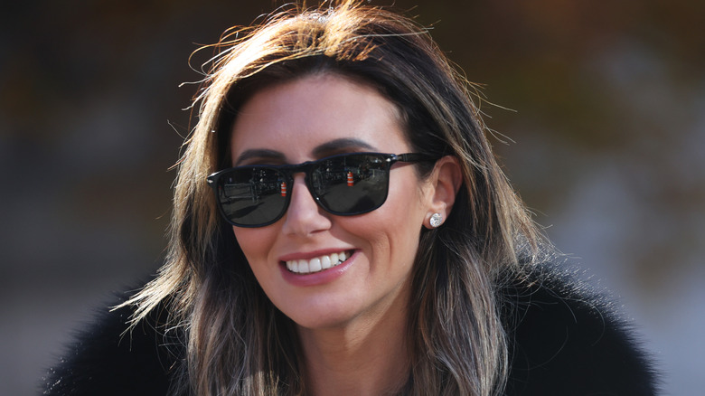 Alina Habba smiling in sunglasses, fur, and diamond earrings