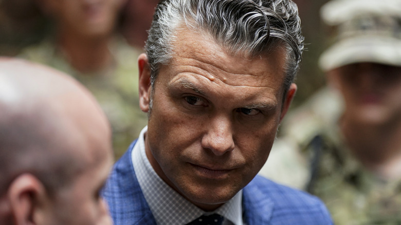 Close up of Pete Hegseth surrounded by men in uniform.