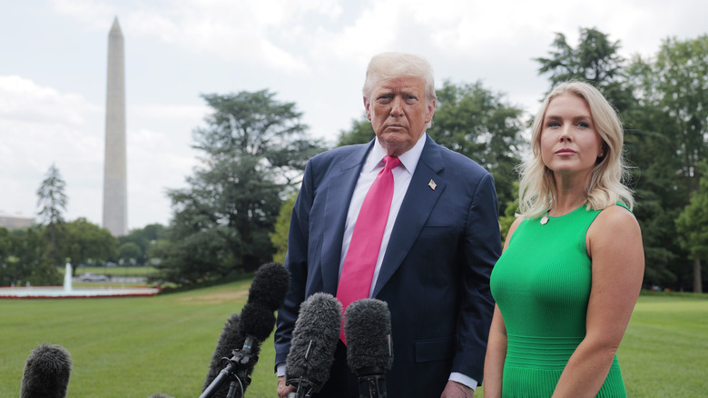 Donald Trump and Karoline Leavitt stand near microphones