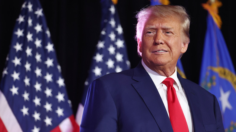 Donald Trump standing in front of American flags